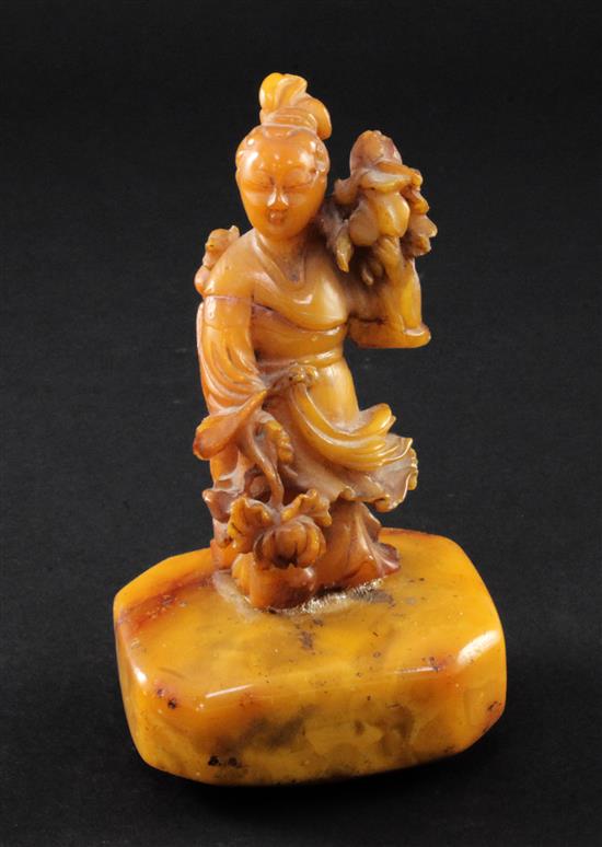 A Chinese egg yolk yellow amber figure of He Xiangu, 20th century, 14cm, glued repairs